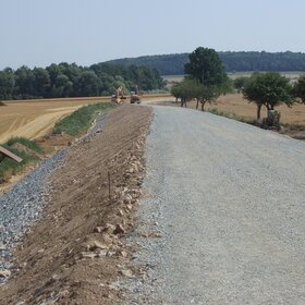 Rural road construction with a gravel surface and construction machinery
