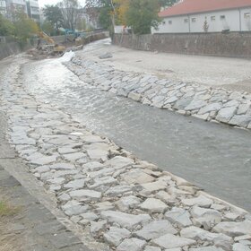 Stream channel with stone reinforcement along the sides and construction work