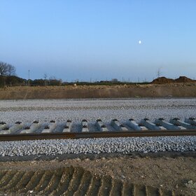 Newly installed railway track with gravel ballast in open terrain