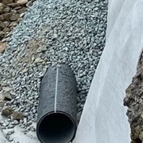 Black pipe laid in a gravel bed 