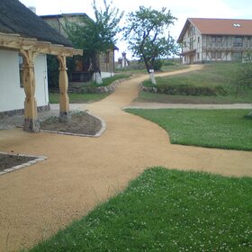 Curved light-colored pathway between buildings and green areas