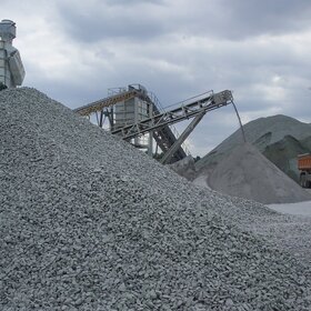 Large stockpiles of grey stone with a conveyor system in the background
