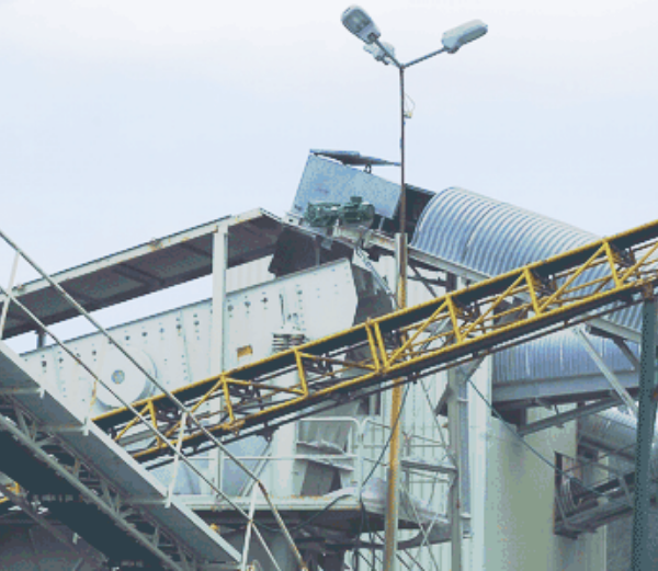 Conveyor belt transporting crushed material and dumping stones onto a rock pile