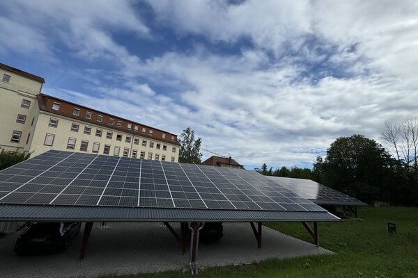 Photovoltaic installation on a carport in front of a historic building complex