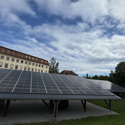 Photovoltaic installation on a carport in front of a historic building complex