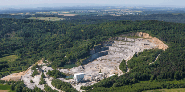 Aerial view of a large hillside quarry surrounded by forest and fields