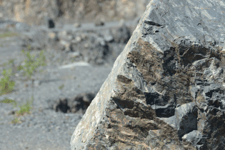 Large angular rock block with dark mineral veins in a quarry